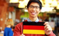 Happy asian student holding flag of germany