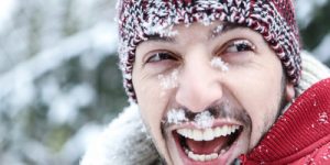 Lachender Mann mit Schnee im Gesicht im Winter