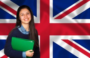 Teen student smiling over English flag Teen student smiling over English flag. Concept of lessons and learning of foreign languages.