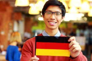 Happy asian student holding flag of germany